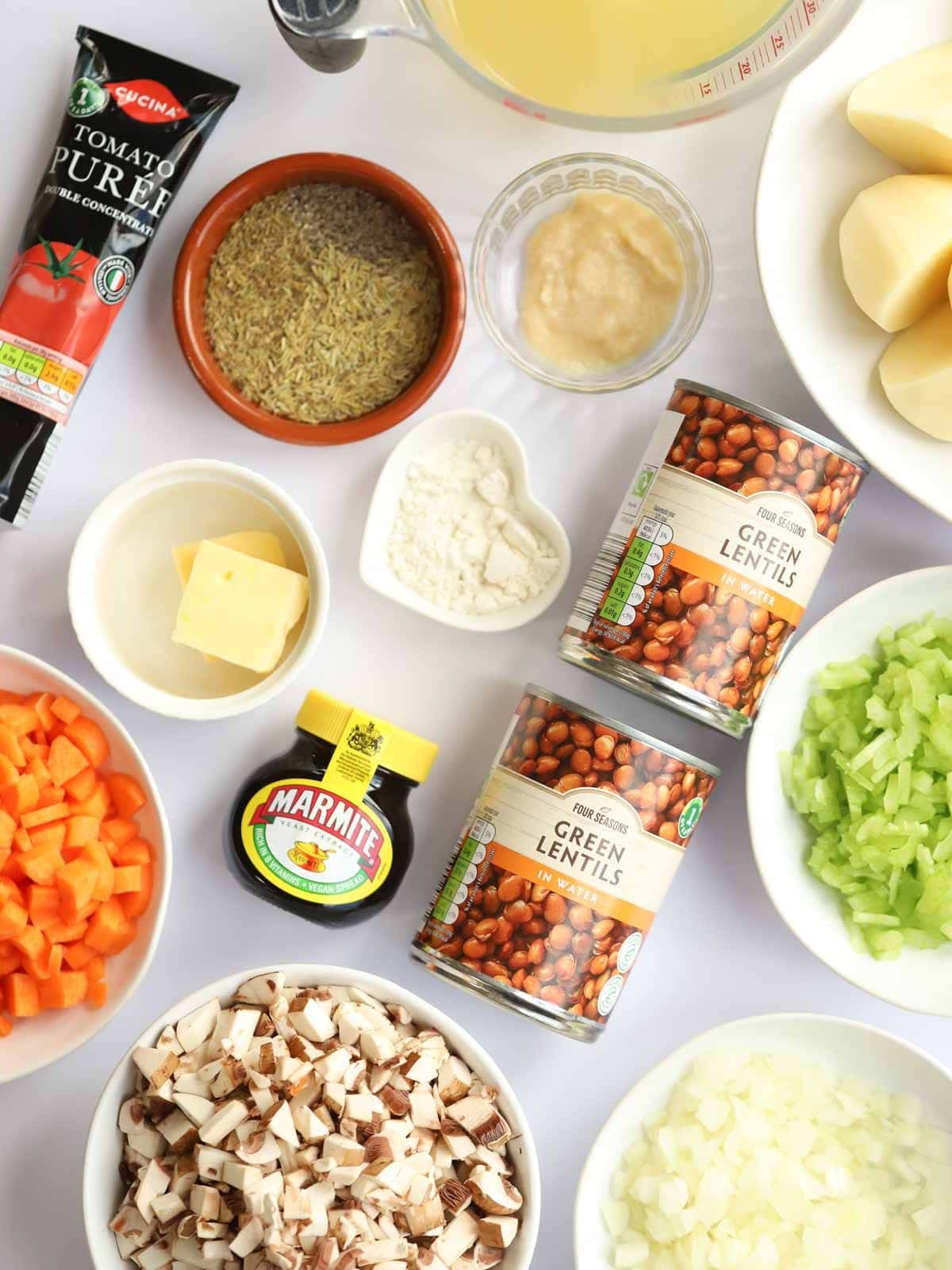 Ingredients for vegetarian cottage pie laid out on a counter top, including tins and dishes.