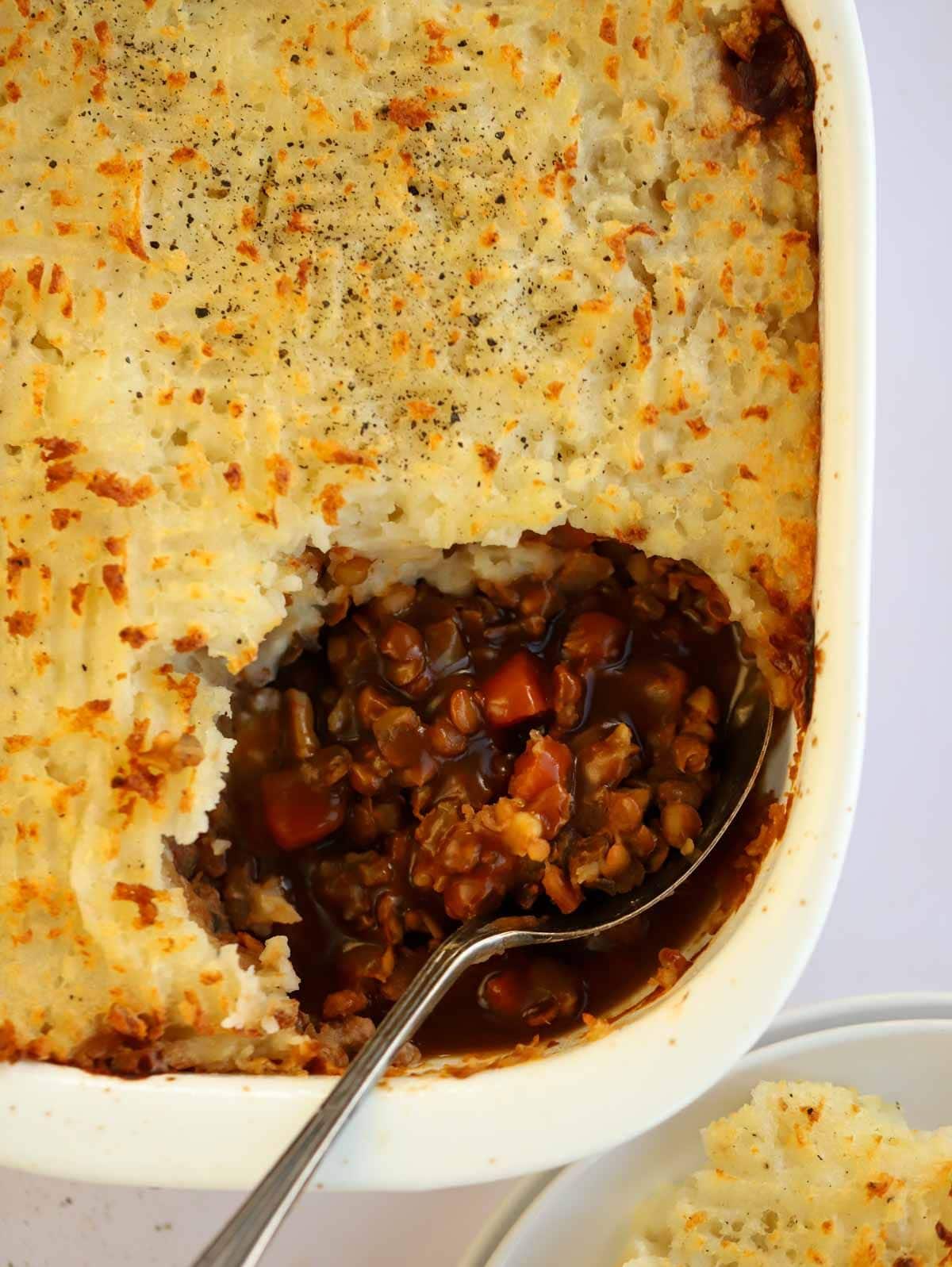 Hearty and comforting Vegetarian Cottage Pie in a dish with a spoon stuck in, ready to serve.