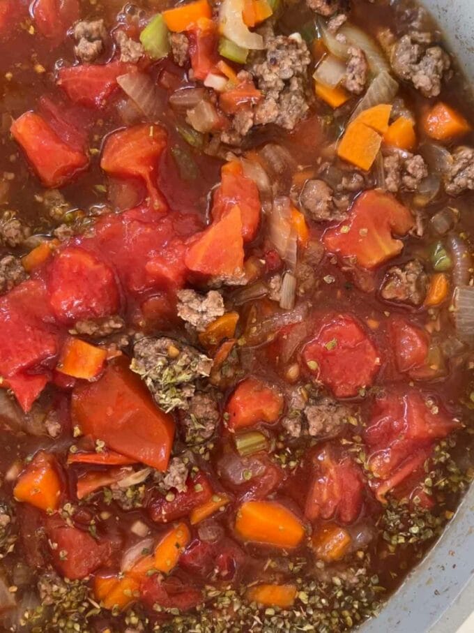 Step 2 in the recipe for Orzo Bolognese. Add tomatoes to the pan.