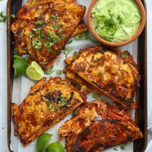 Fried chicken tacos with tomato sauce and pulled chicken, melted cheese and an avocado dip on the side.