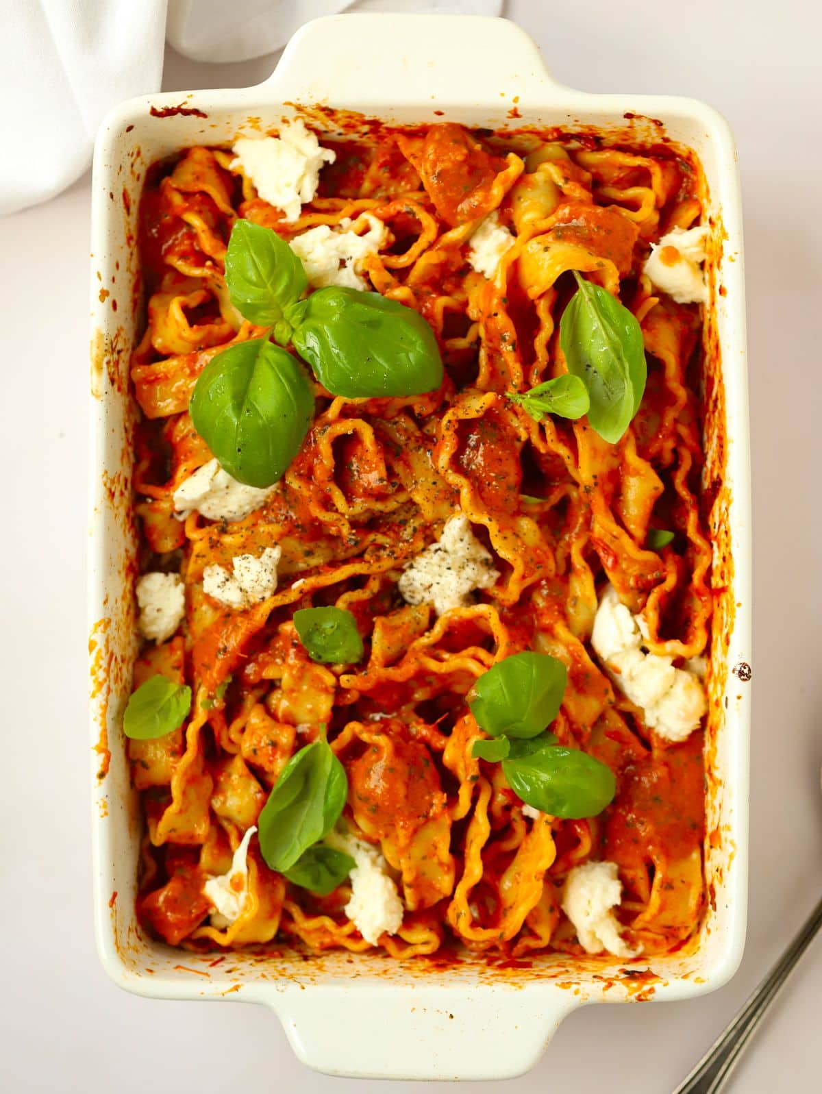 An oven dish filled with tomato and basil pasta, topped with mozzarella.
