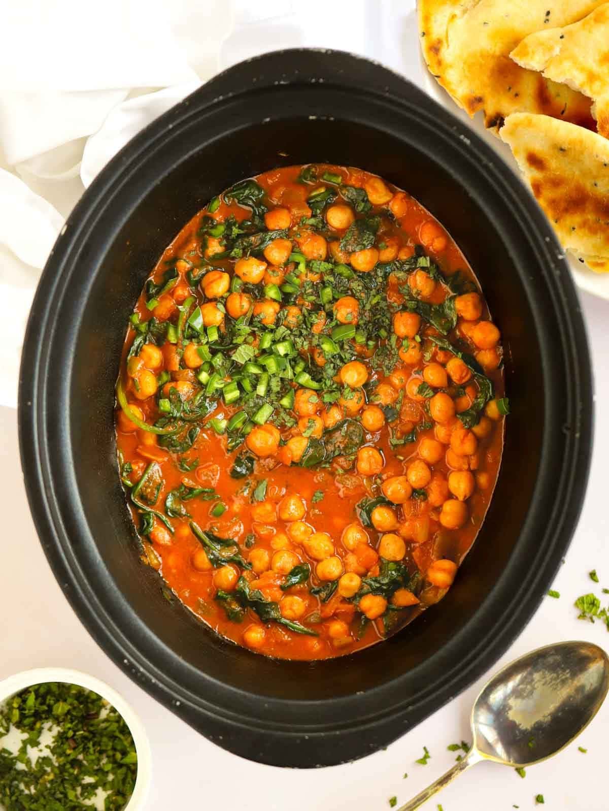 Slow cooker pan filled with chickpeas and spinach.