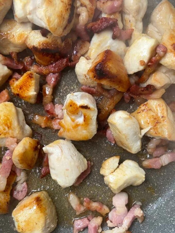 Step 1 in the recipe for BBQ Chicken Pasta. Fry the chicken and bacon in a pan.