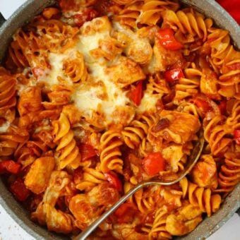 A pan with pasta, chicken, bacon, cheese and peppers, ready to be served.