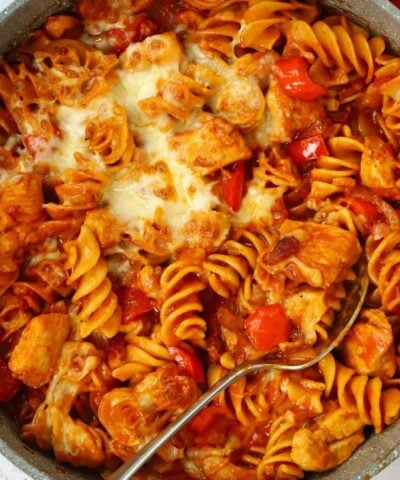 A pan with pasta, chicken, bacon, cheese and peppers, ready to be served.