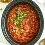Slow cooker filled with cooked homemade Baked Beans.
