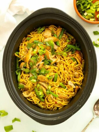 Slow cooker filled with cooked curried chicken noodles.