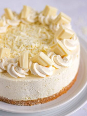 A no bake white chocolate cheesecake on a plate, ready to eat.