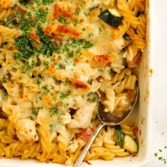 Creamy Chicken and Bacon Pasta Bake in a dish, with a spoon ready to serve.