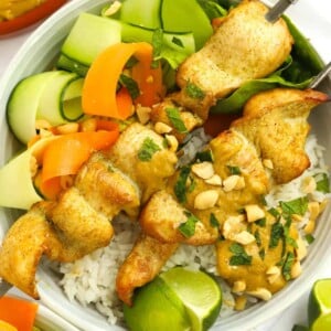 Chicken Satay recipe on a bed of rice and salad.