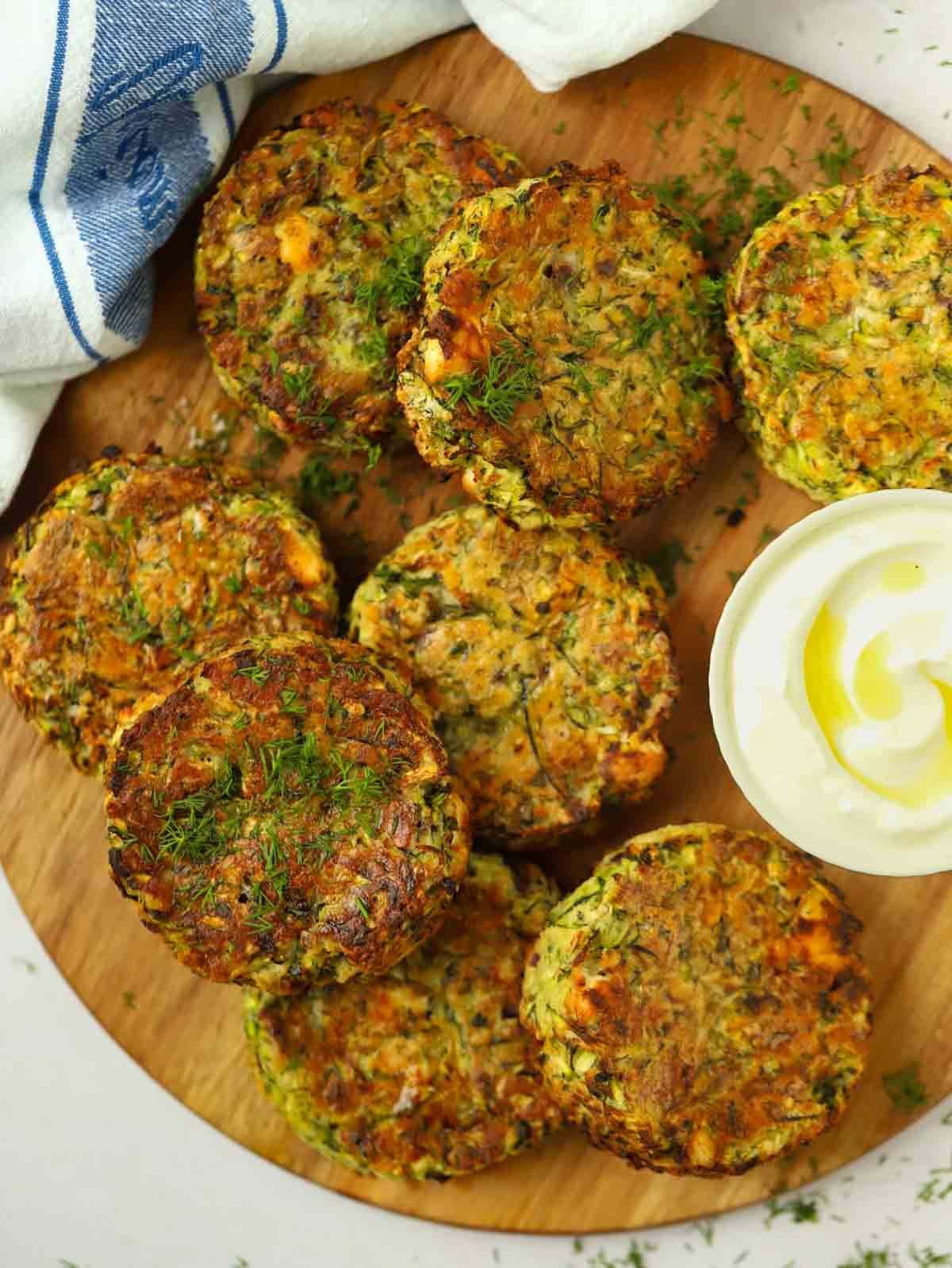 Eight round courgette fritters on a chopping board ready to eat.