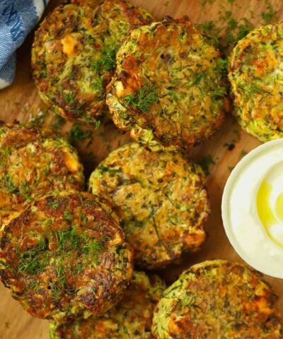 Courgette fritters on a board with a creamy dip.