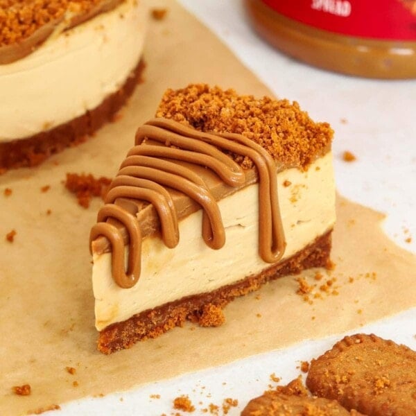 A slice of homemade Biscoff Cheesecake with a base, filling and topping drizzled over.