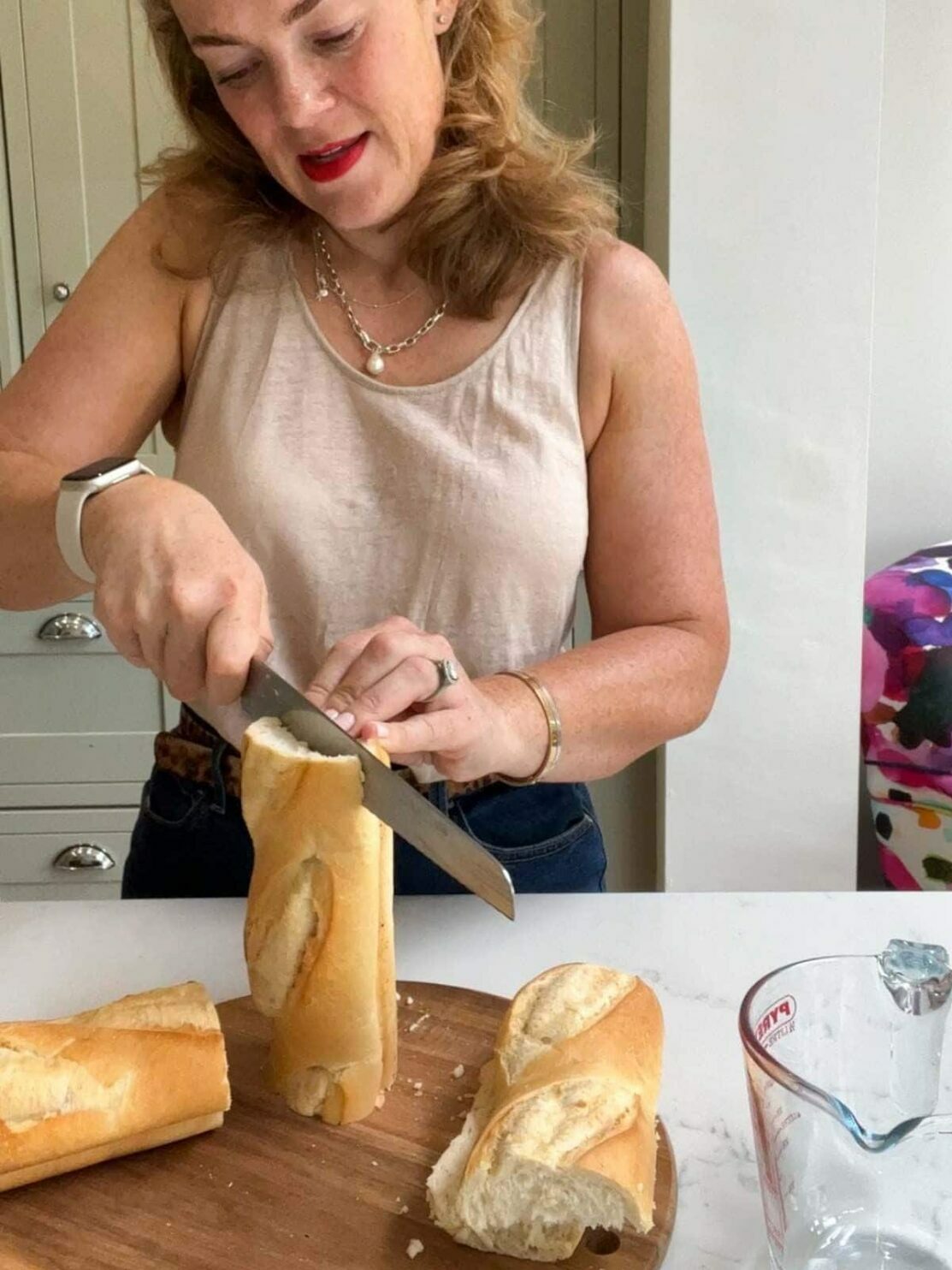 Sarah Rossi of Taming Twins demonstrating how to make french bread pizza step 1. Cutting the baguette lengthways in half.