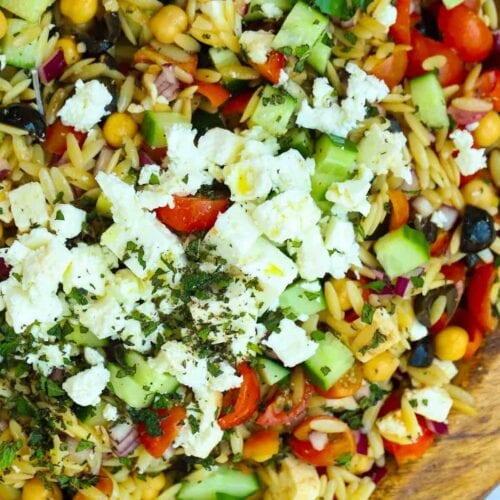 Bowl full of orzo pasta salad, with colourful ingredients.