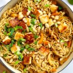 Satay-style peanut butter noodles with halloumi in a big pan.