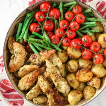 Pesto chicken bake in a dish with green beans, tomatoes and potatoes.