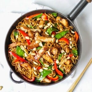 Overhead photo of pork stir fry recipe with noodles, pork, red peppers and mange tout and peanuts.