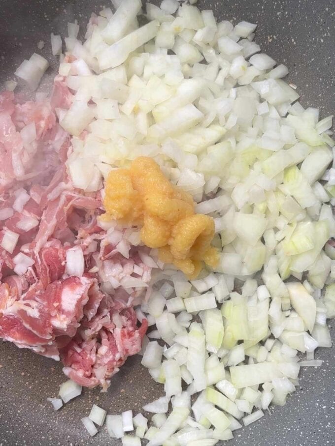 Onions, bacon and garlic in a pan frying for the recipe Bacon Pasta. Step 1.