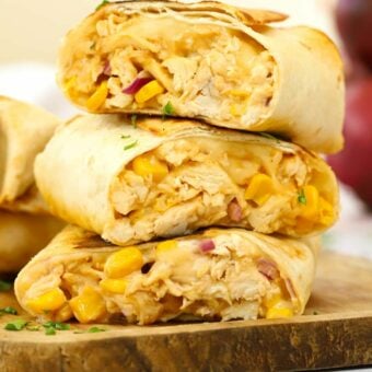 A stack of sliced cooked chicken wraps with cheese and sweetcorn, ready to serve.