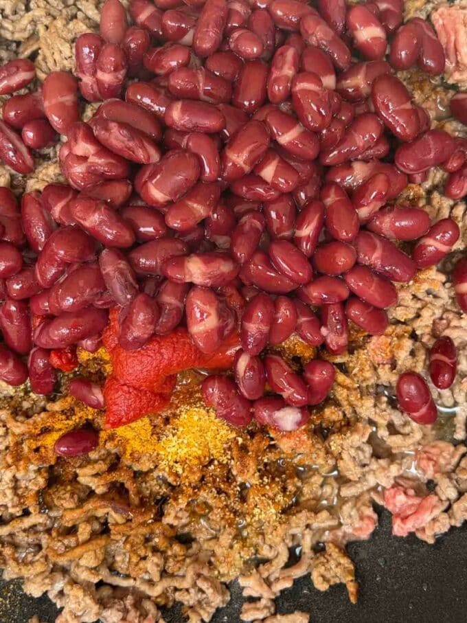 Mince beef in a pan with kidney beans and flavouring for step 1 in the recipe for Beef Tacos.