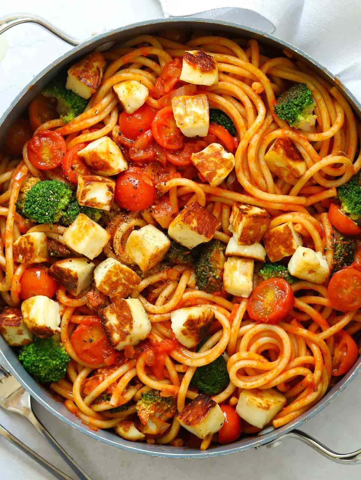 A big pan filled with cooked Halloumi Pasta with broccoli and tomatoes.