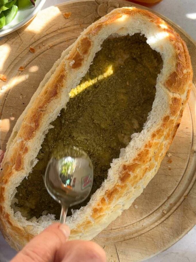 How to make a picnic loaf, step 2. Spread pesto on the bottom of the hollowed out loaf.