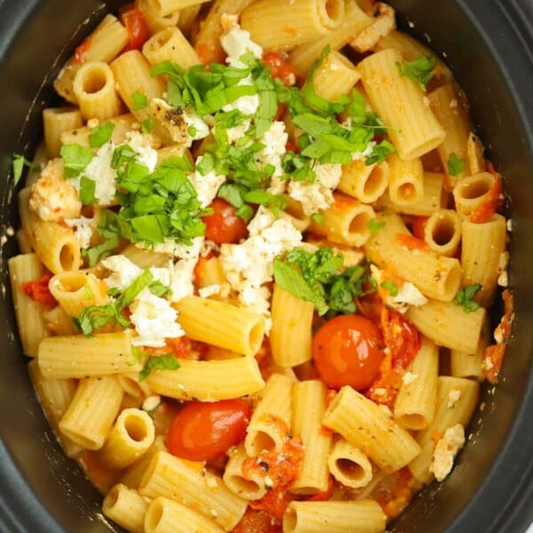 A close up of pasta mixed with feta cheese and tomatoes for a slow cooker take on the viral Tik Tok recipe Feta and Tomato Pasta.