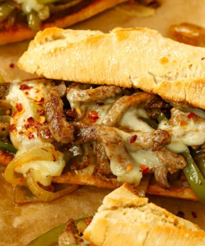 A baguette filled with hot melted cheese and steak for a homemade Philly Cheesesteak that's ready to eat.