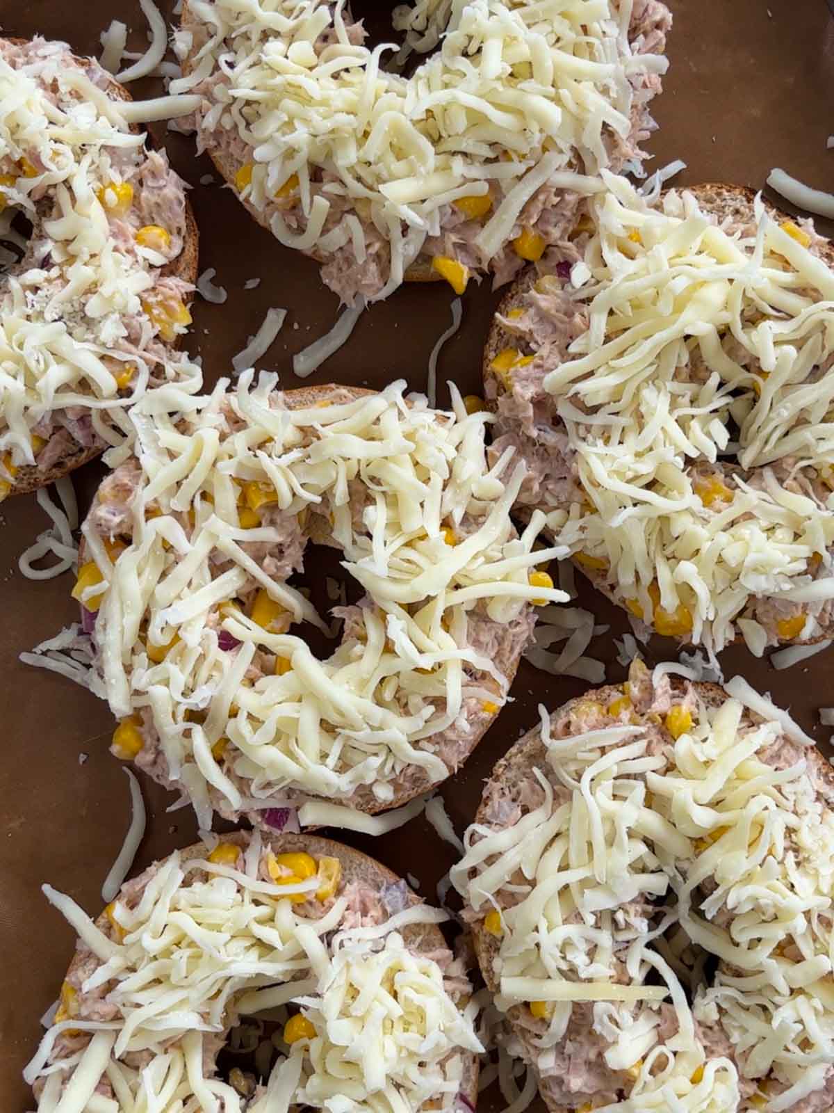 Step 4 of making tuna melt bagels topped with cheese, ready to go in the oven.