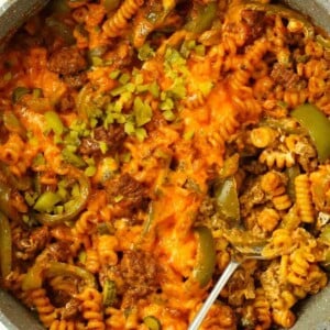 A pan with cooking Cheeseburger Pasta, with a spoon ready to serve.