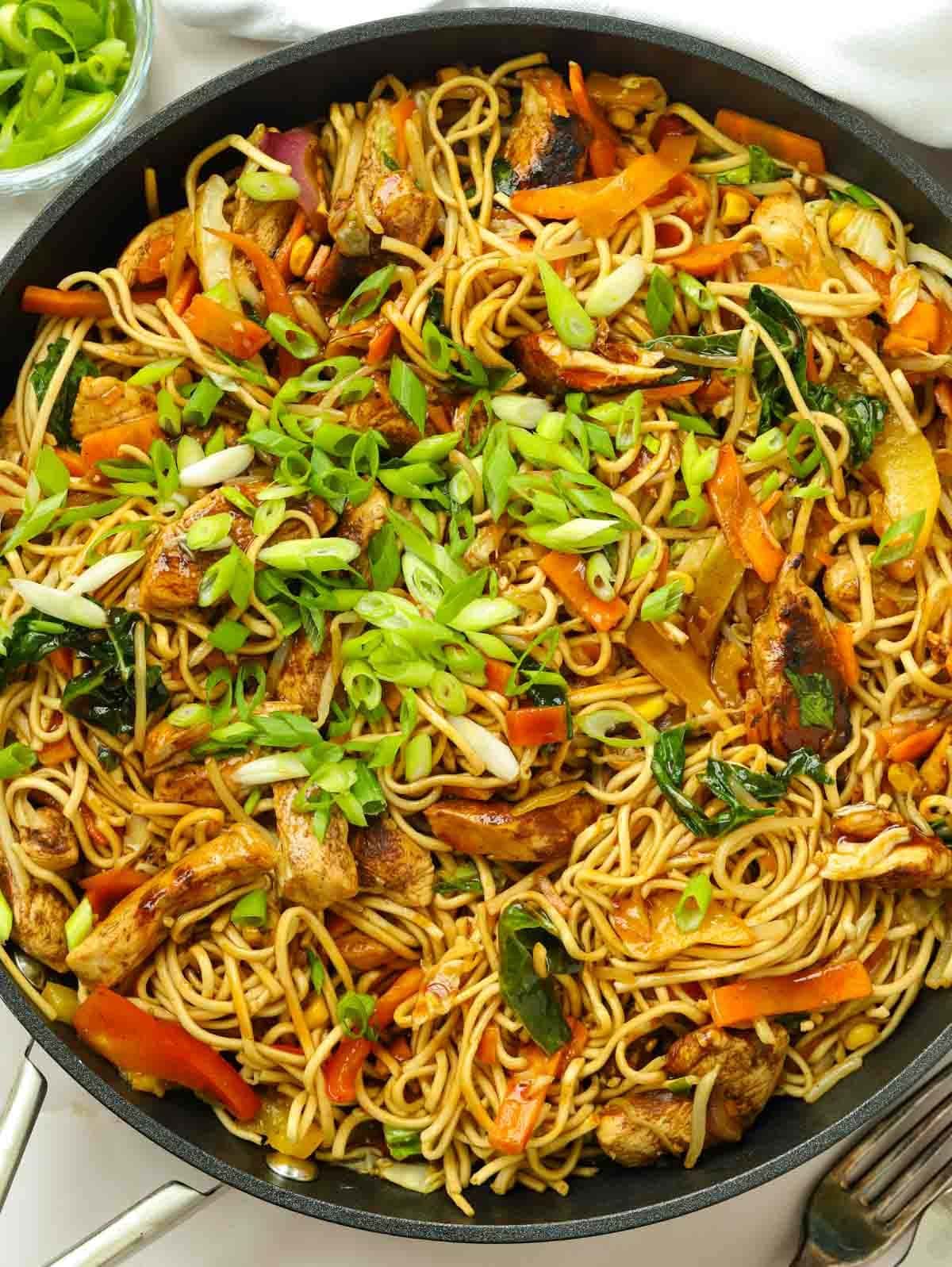 A big pan filled with chicken chow mein, ready to serve.