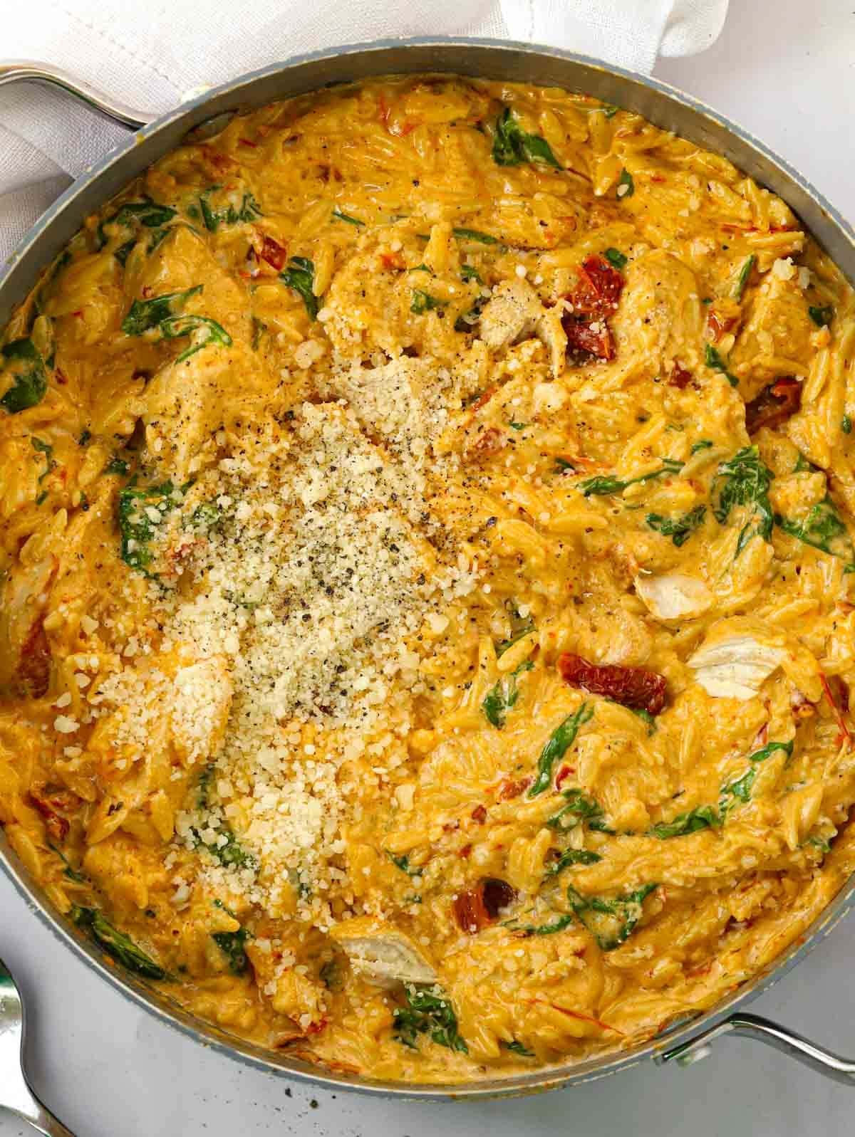 A big pan filled with the recipe Marry Me Chicken Orzo, with sun-dried tomatoes and parmesan. Delicious.