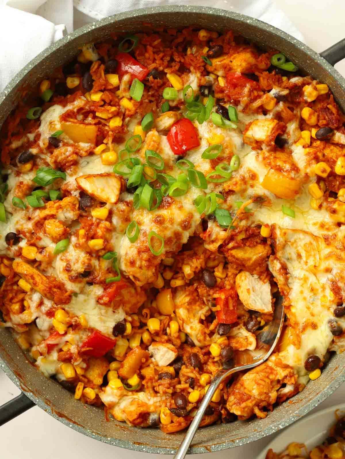 A big pan full of cooked Mexican Chicken with rice and peppers and beans. Ready to eat.