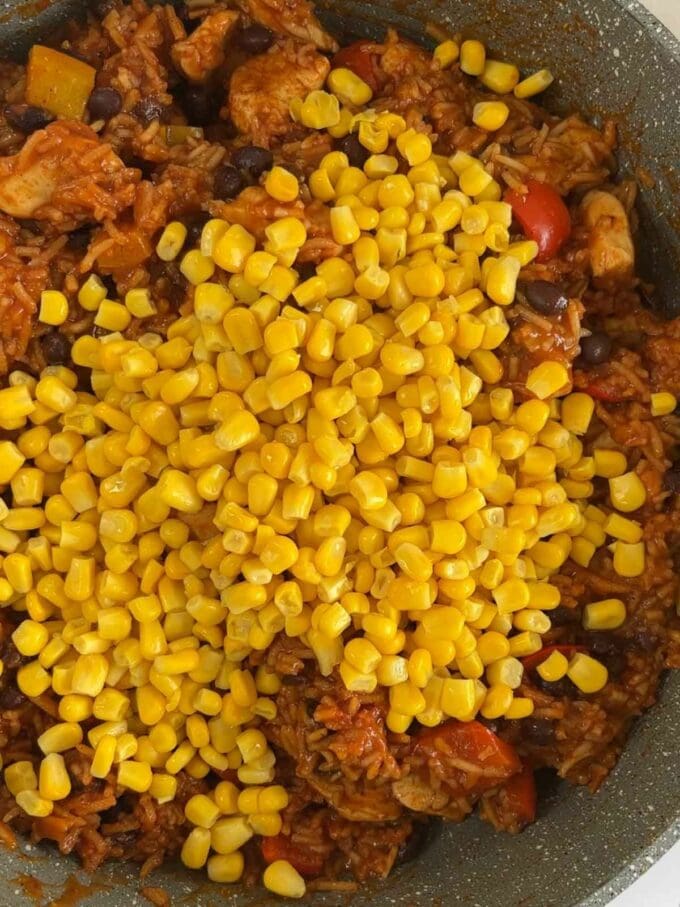Step 3 in the recipe Mexican Chicken and Rice One Pot. Sweetcorn going into a big pan of ingredients.
