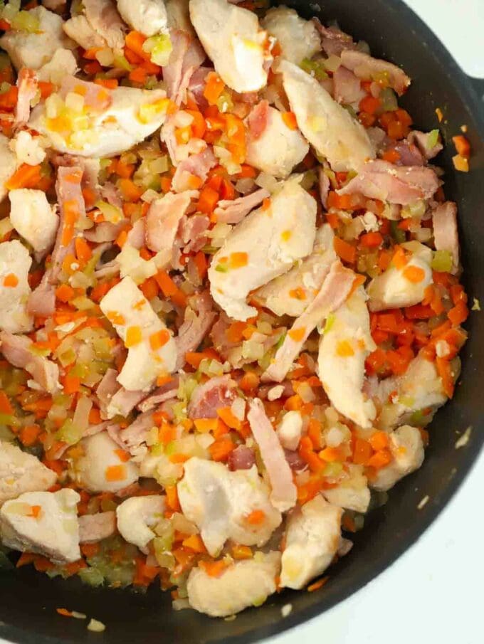 A pan filled with chicken and bacon with vegetables for the first step in the recipe for Chicken Pie.