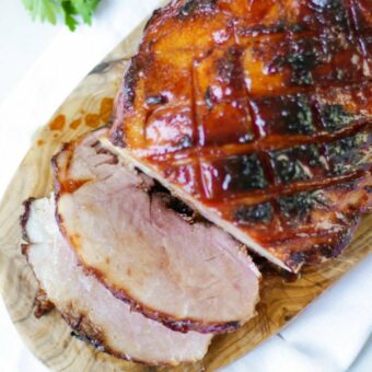 A cooked gammon joint on a board with a honey glaze.