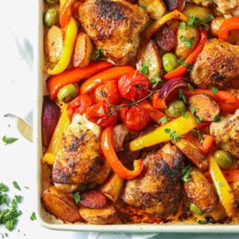 A tray of cooked chicken and chorizo with roasted vegetables, ready to eat.