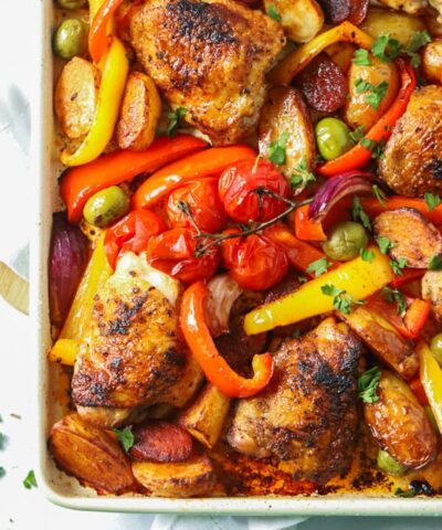 A tray of cooked chicken and chorizo with roasted vegetables, ready to eat.