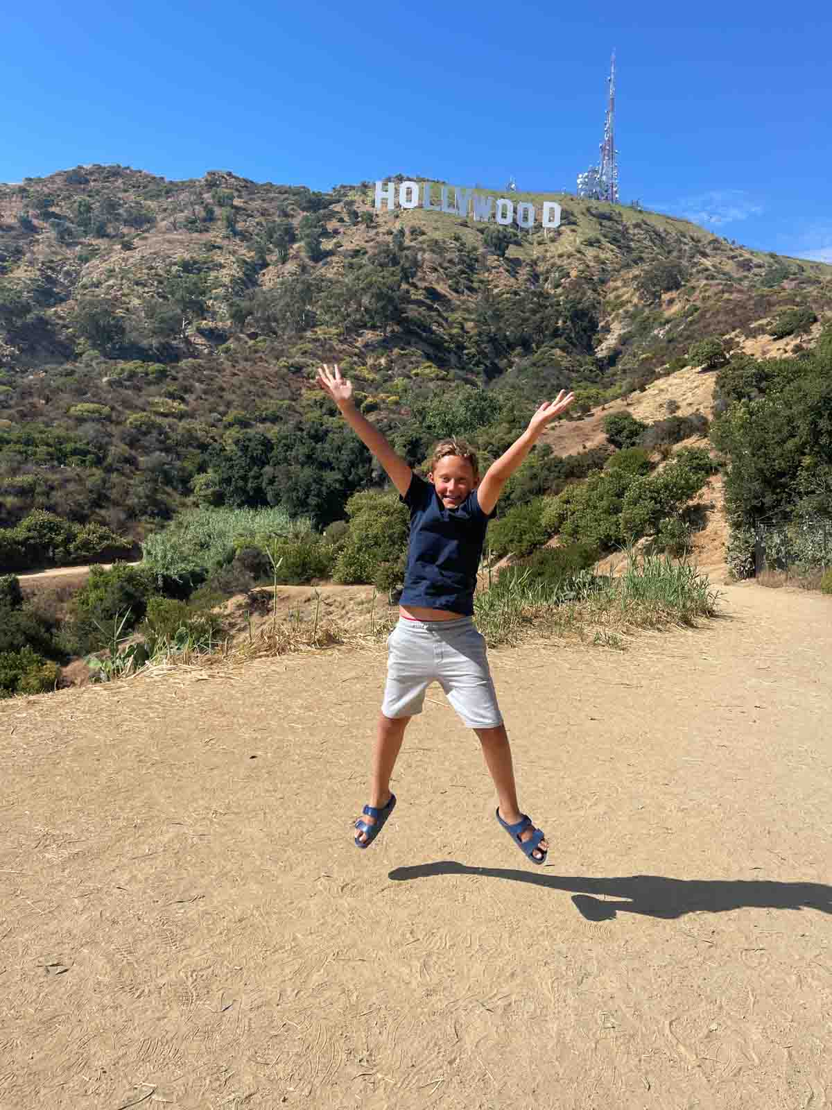 Boy jumping in front of the Hollywood sign.