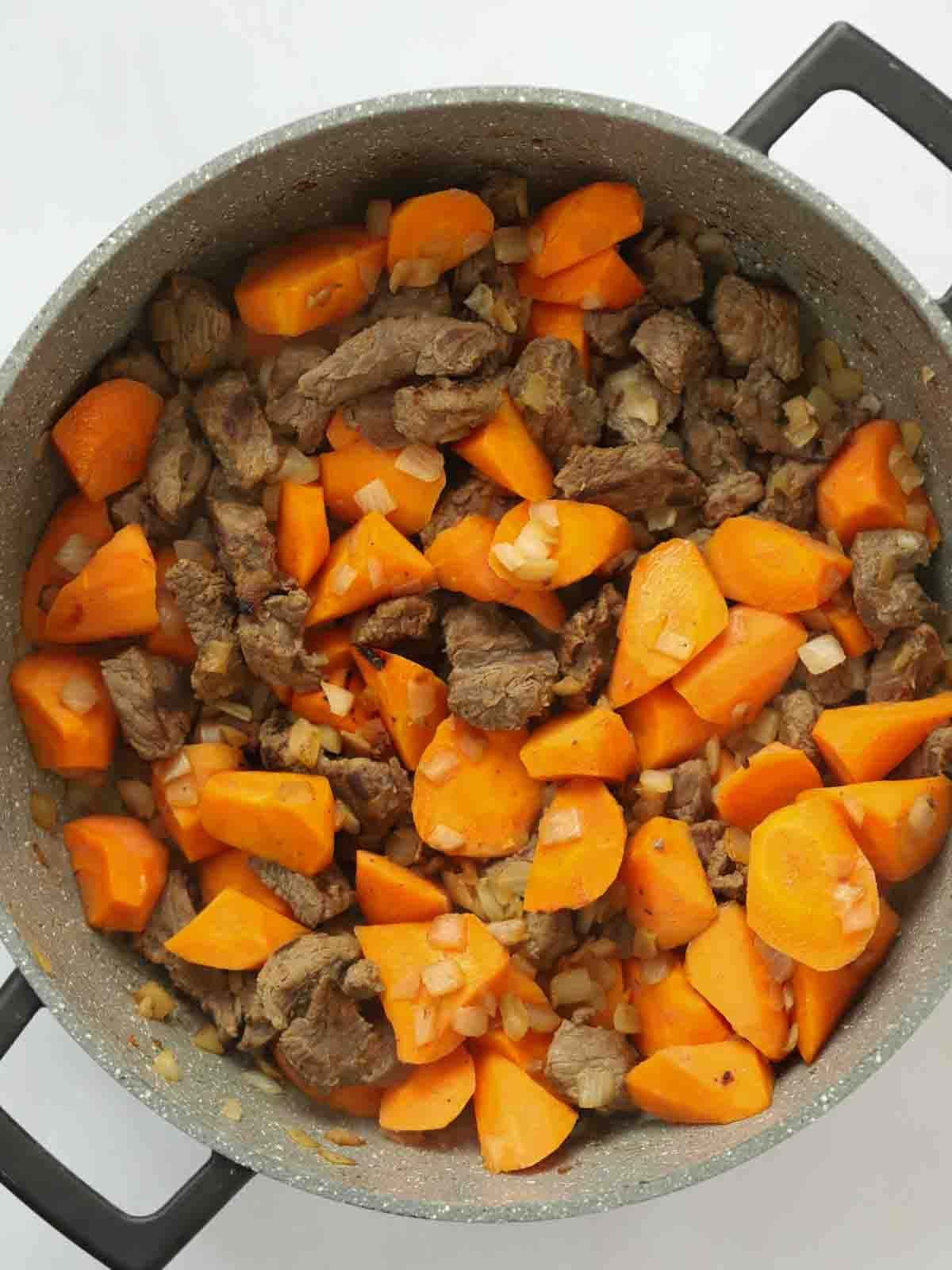 Cooked dice beef with carrots and onion in a large pan for the recipe Steak Pie, step 1.