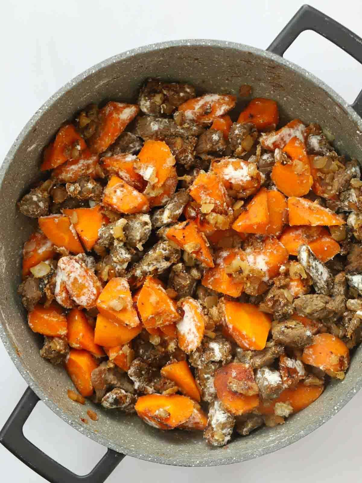 Cooked beef, carrots, onion and flour in a large pan for step 2 of the recipe for Steak Pie.