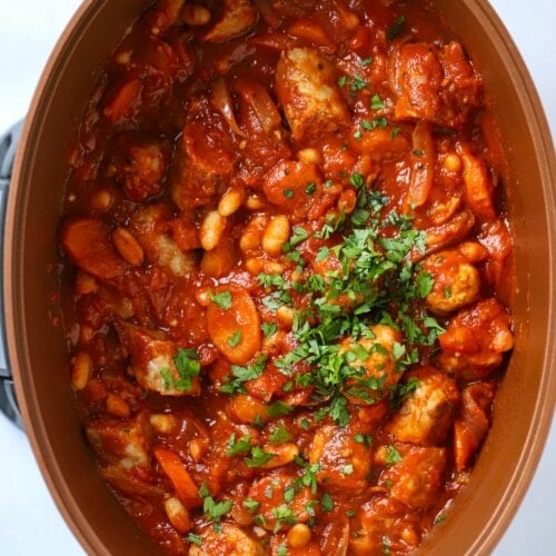 A large slow cooker pan filled with cooked sausage and bean casserole.