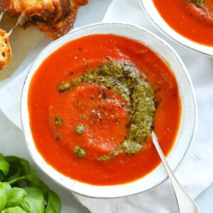 Easy tomato soup recipe with a swirl of pesto in a white bowl.