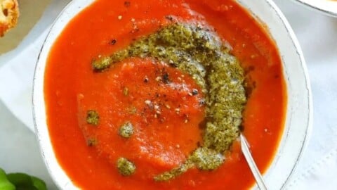 Easy tomato soup recipe with a swirl of pesto in a white bowl.