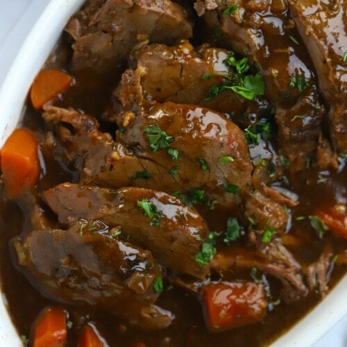 A dish filled with slow cooked beef joint with carrots and gravy. Ready to serve.