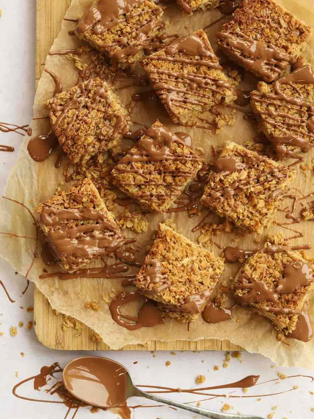 A chopping board filled with squares of chocolate-covered flapjacks.