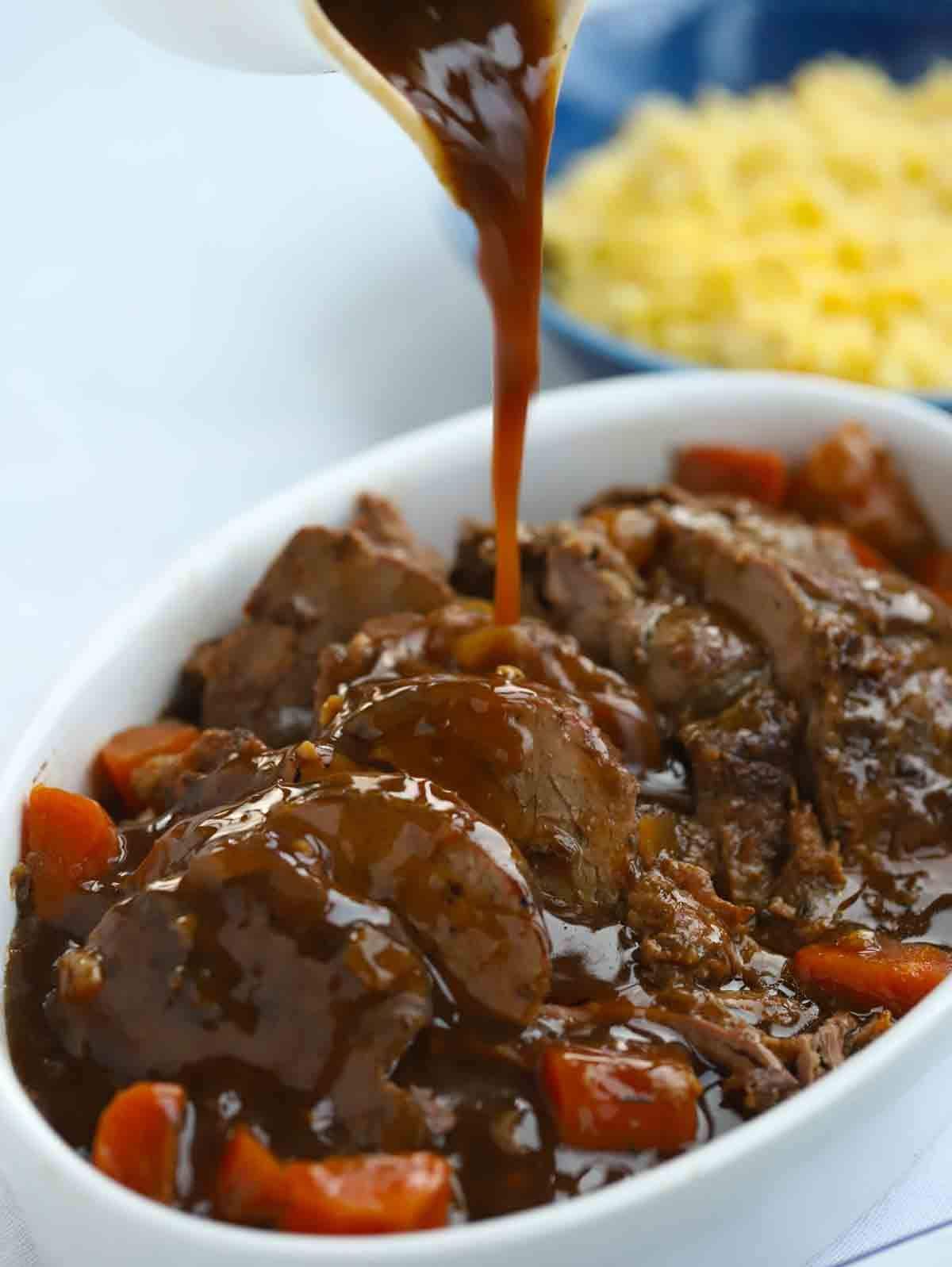 Sliced Roast Beef with gravy being poured over it.