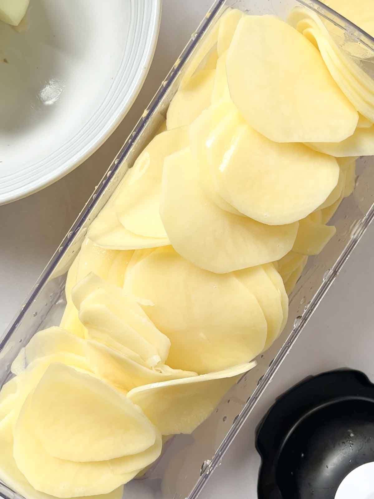 Finely sliced potatoes in a container, ready to make Boulangere Potatoes.