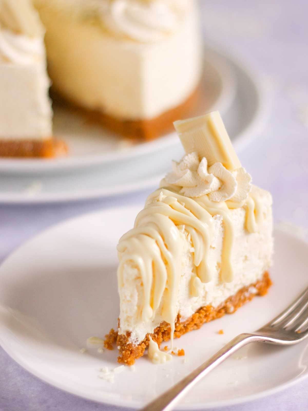 Slice of white chocolate cheesecake on a plate with fork.